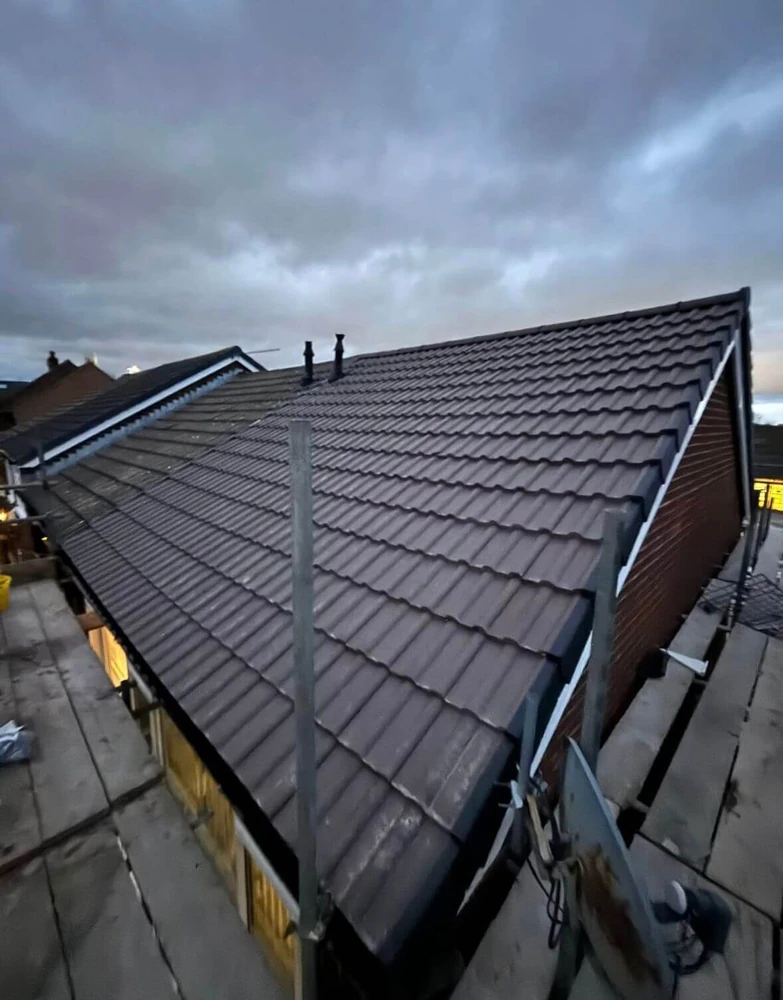 Dark tiled mono-pitch roof on a garage extension above a flat roof section